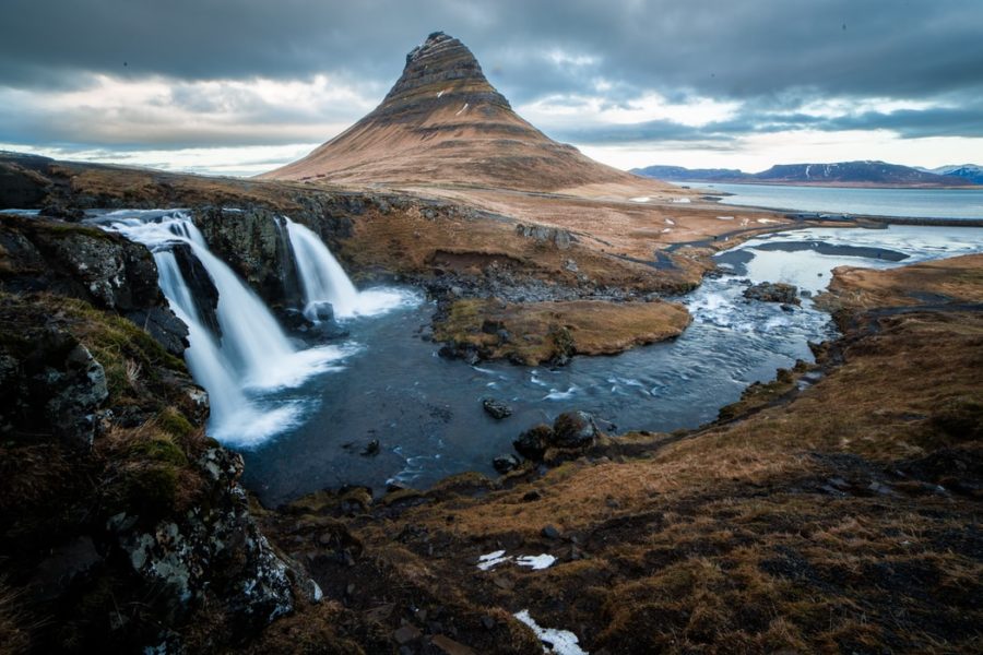 Die Wasserfälle des Kirkjufellsfoss strömen durch eine karge Landschaft auf Island. Foto: Unsplash/Martin Jernberg.