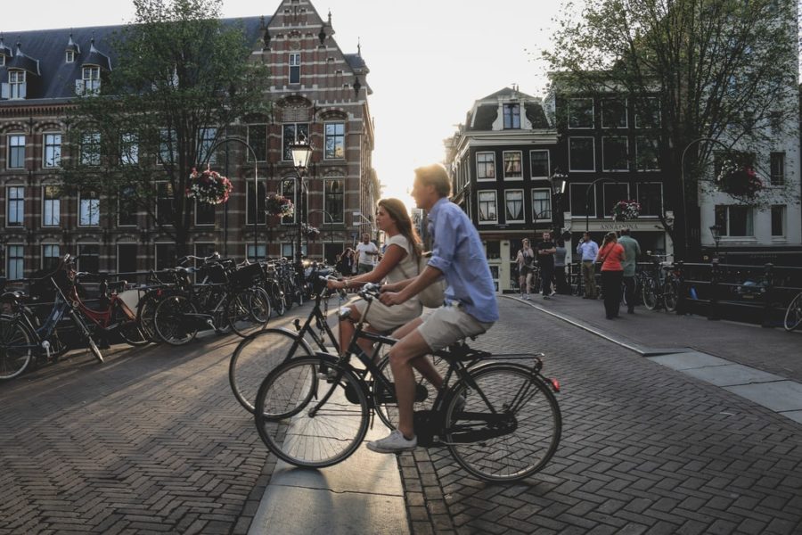 Junge Menschen fahren auf Fahrrädern durch Amsterdam. Foto: Unsplash/Sabina Fratila.