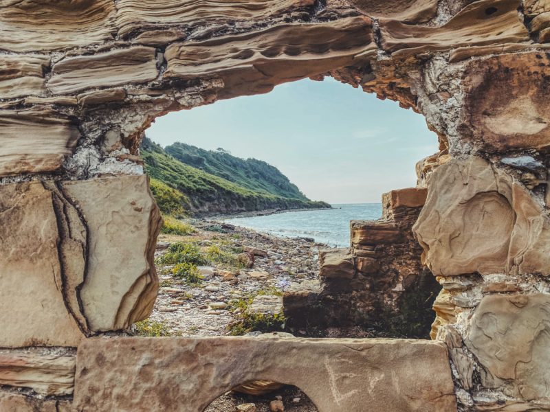 Blick aus einer Steinhöhle auf den Steinstrand