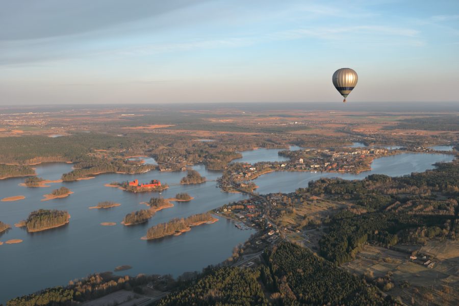Ein Heißluftballon fährt über eine Seenlandschaft mit vielen kleinen Inseln. Foto: Unsplash/Maksim Shutov.