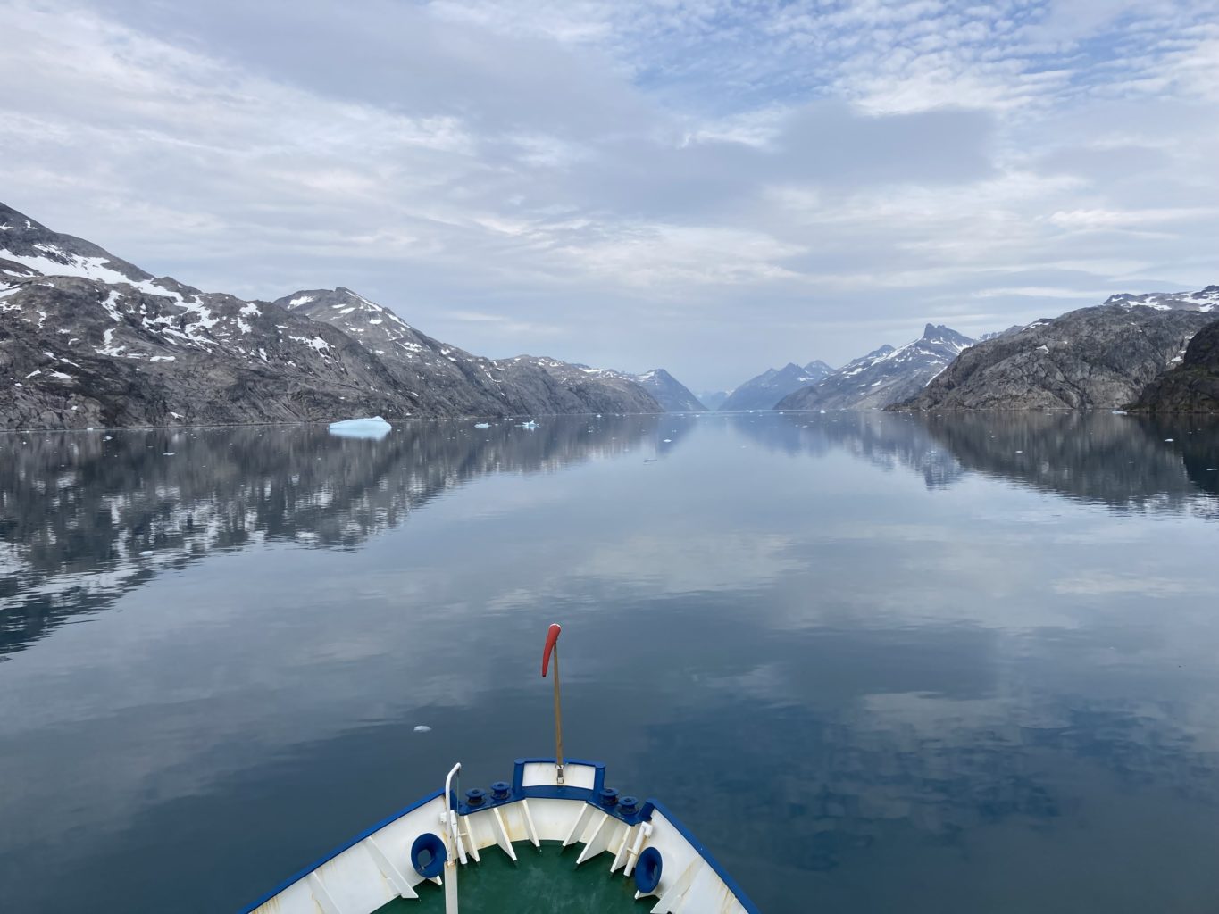 Eine Bootsspitze, die auf einem spiegelglatten Bergsee fährt