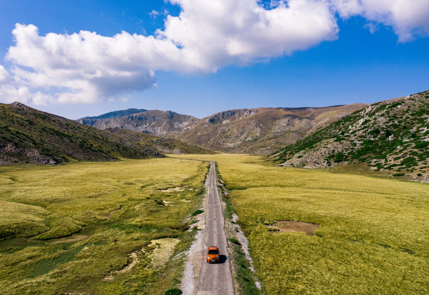 Eine einsame Straße führt durch eine Berglandschaft.