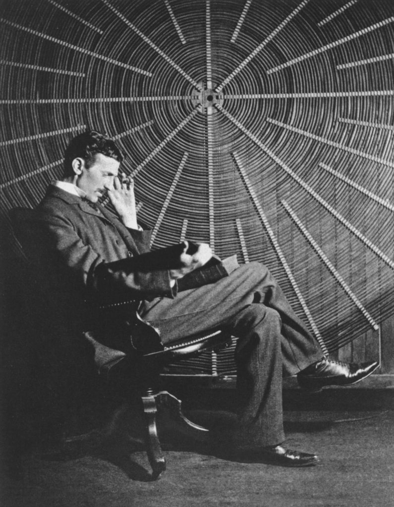Ein Mann liest vor einer riesigen Spiralspule. Foto: Gemeinfrei