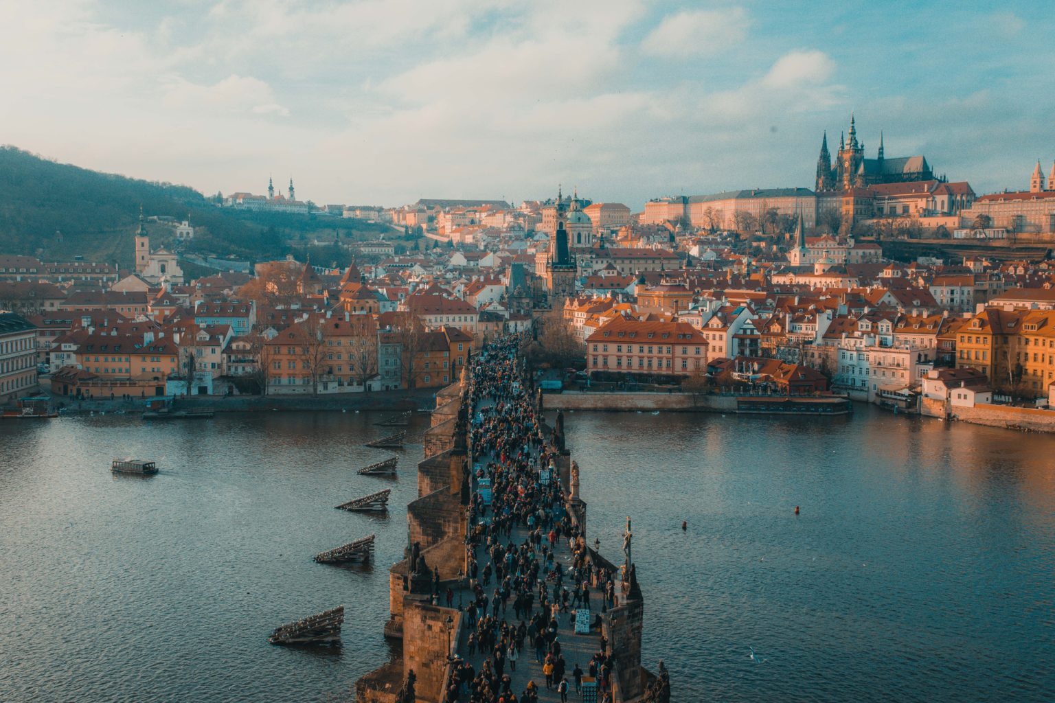 Viele Menschen laufen über eine große Brücke, im Hintergrund ist die Altstadt Prags zu sehen