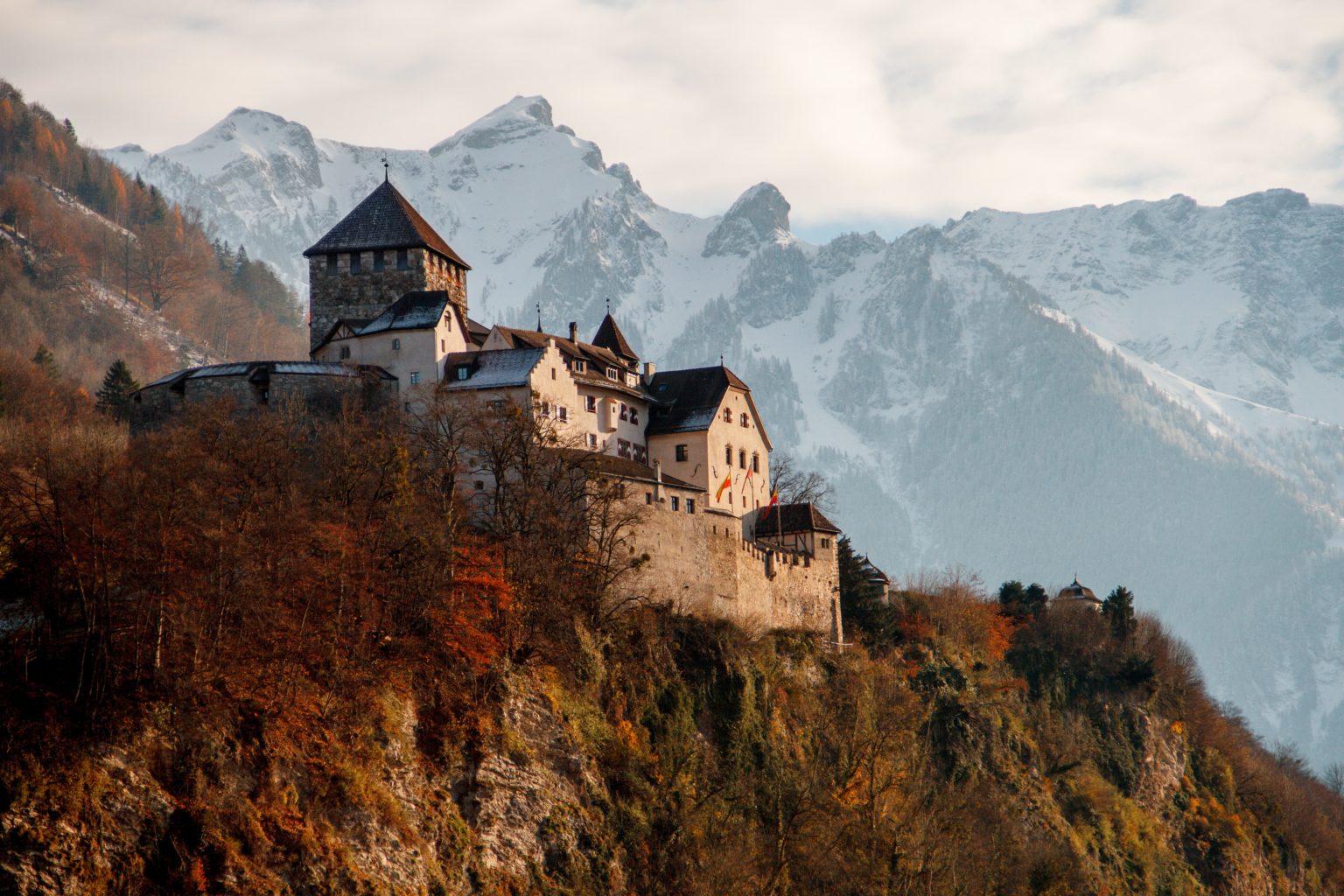 Das Schloss Vaduz thront an einem Berghang. Im Hintegrund sind hohe schneebedeckte Berge zu sehen. Foto: Unsplash/Henrique Ferreira.