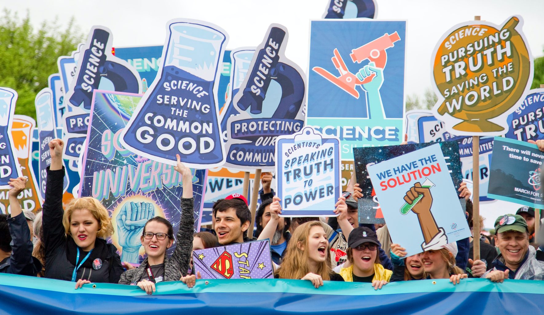 Junge Menschen demonstrieren mit Schildern für die Wissenschaft.